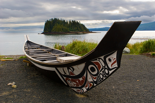 Family paddles canoe down stream at sunrise