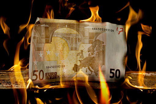 Banknotes burn in the gas flame of the stove