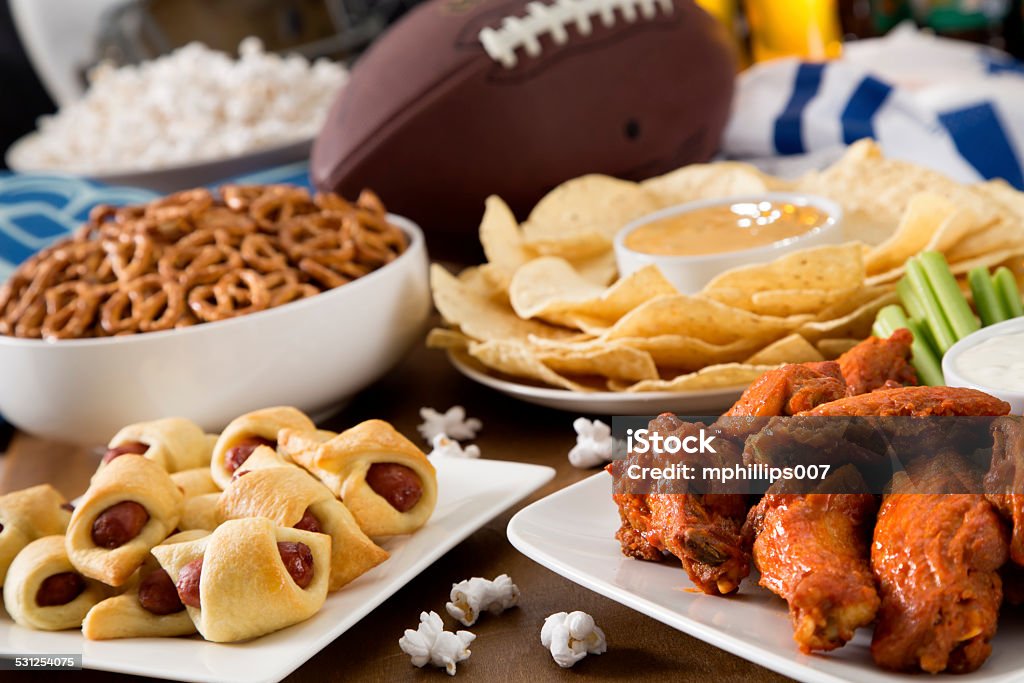 Tailgate Food Hot wings, nachos, pigs in a blanket, beer, and popcorn, a tailgate party spread.  Please see my portfolio for other food and drink images. American Football - Sport Stock Photo