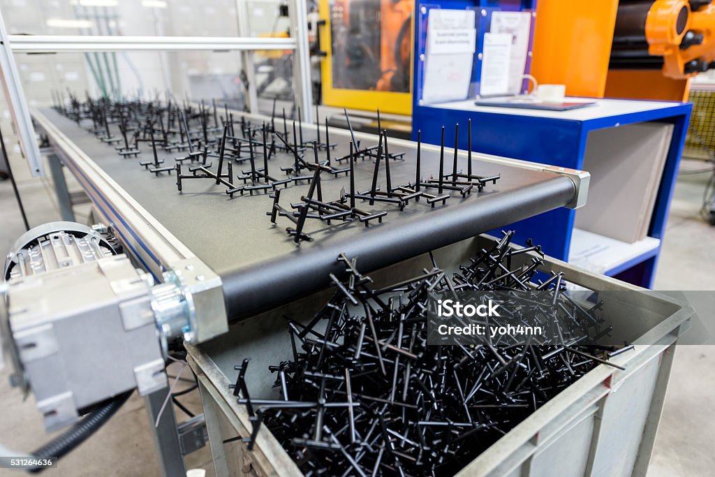 Automated conveyor belt with plastic goods Horizontal color image of automated conveyor belt line in factory with plastic pieces. Plastic Stock Photo