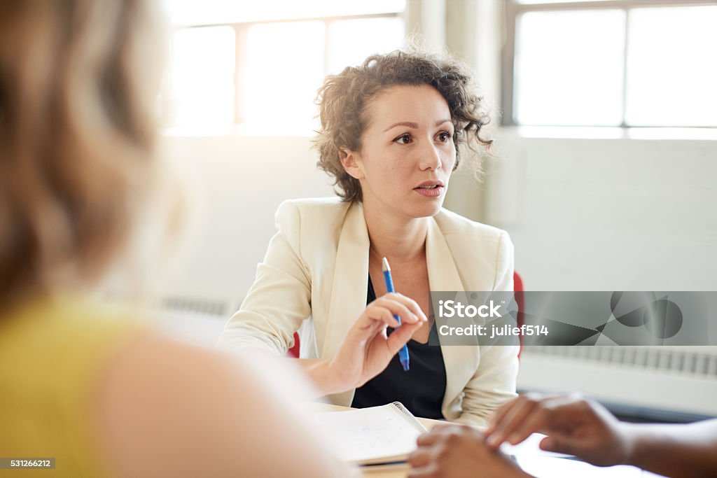 Unposed group of creative business people in an open concept Candid picture of a female boss and business team collaborating. Filtered serie with light flares, bokeh, warm sunny tones. Serious Stock Photo