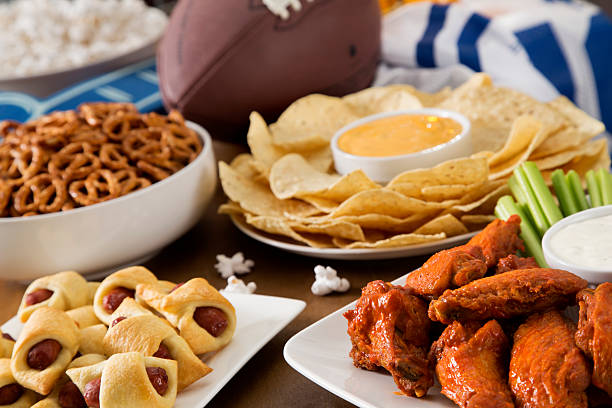 Tailgate Party Tailgate party spread with hot wings, pig in a blanket, nachos, pretzels, and popcorn with football and a football jersey. tailgate party photos stock pictures, royalty-free photos & images