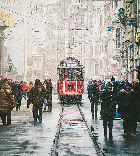 Nostalgic Trams passing through Crowded Istiklal street in a snowy winter day in Taksim, Beyoğlu, Istanbul, Turkey.