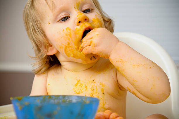 istock Baby Eating While Covered with Food in High Chair 531268579
