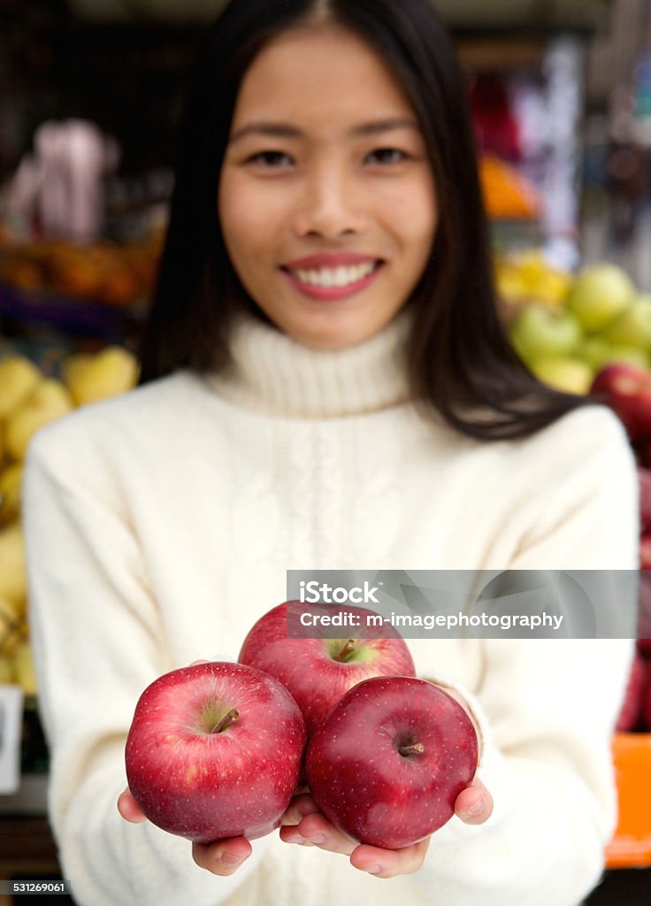 Smiling young woman holding fresh organic red apples in hand Close up portrait of a smiling young woman holding fresh organic red apples in hand 20-29 Years Stock Photo