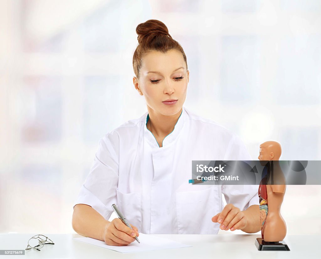 Beautiful mid-age female doctor sitting at the table Doctor  standing by her desk and looking at camera 2015 Stock Photo