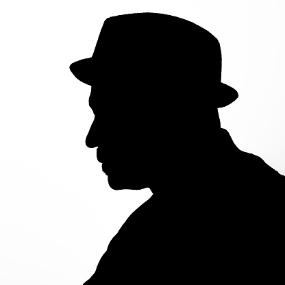 Black silhouette of a man wearing a hat and a mustache in black against a white background.