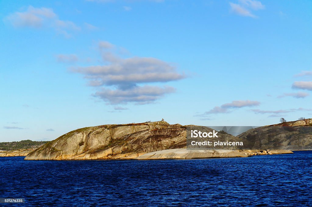 Rocky island in Fjord Rocky island in the middle of the fjords in autumn. Around the blue water and blue nioeb Telemark region of Norway 2015 Stock Photo
