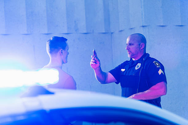 Policeman performing sobriety test on driver Police officer giving a sobriety test to a young man who he suspects is driving under the influence of drugs or alcohol.  Police cruiser is out of focus in the foreground. driving under the influence stock pictures, royalty-free photos & images