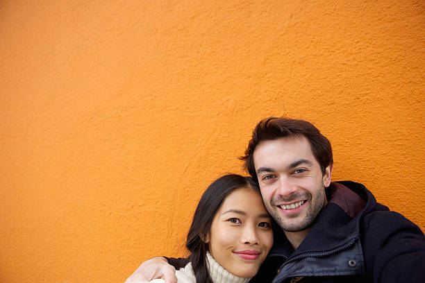 istock Cute couple smiling on orange background 531289159