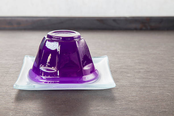 Purple grape jelly on dish on wooden background with copyspace.