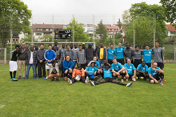 Scharnhausen, Germany - May 14, 2016: Happy group photo after the team of TSV Scharnhausen was playing a friendly match of soccer against a team of refugees that is residing in a camp in Scharnhausen for 6 months now. Since a lot of the young refugees coming from Africa, Asia and Arabic countries like playing football, matches like these are an important step regarding the integration of these people in Germany and whole Europe. 