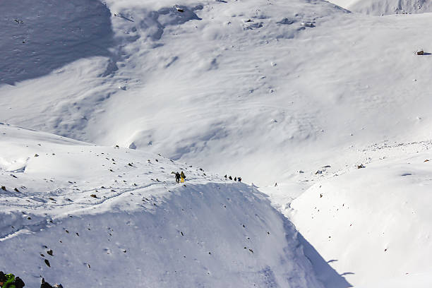 istock Team of mountaineers going toward summit with snow and wind 531305980