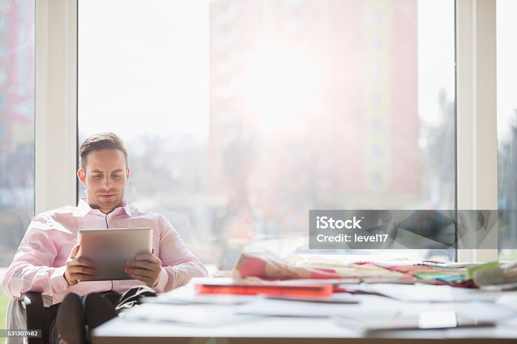 Businessman using digital tablet at conference table in creative office Young businessman using digital tablet at conference table in creative office Digital Tablet Stock Photo