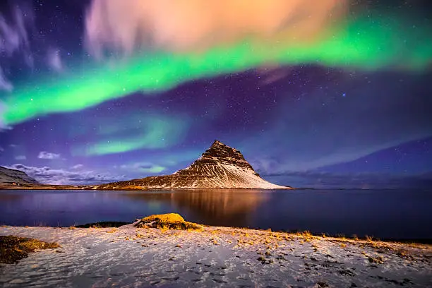 A typical Nordic nightscape and very famous location for travelers and adventurers from all over the world - the ''Church mountain'' Kirjuffell under the spectacular celestial lights Aurora Borealis, which makes Iceland popular spot for tourist willing to witness one of the greatest natural phenomenoms. Shot with Canon EOS 60D, wide angle lens, f2.8, ISO 1600, long exposure of 10 seconds.