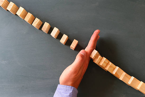 istock male hand stopping the domino effect 531313332