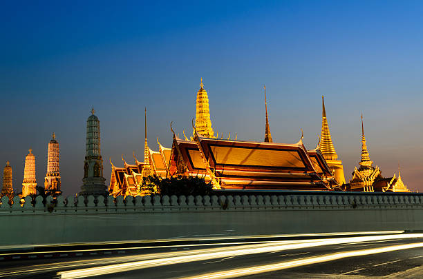 золотой дворец в вечернее время с двигаться автомобиль свет - bangkok thailand rickshaw grand palace стоковые фото и изображения