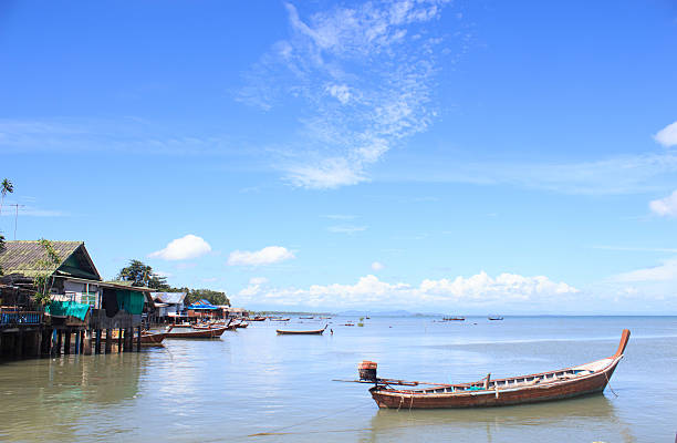 istock wooden long-tail boat on blue sea water and sunlight reflect 531317704