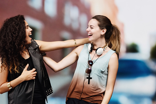 Two cheerful women laughing in front of urban scenehttp://www.twodozendesign.info/i/1.png