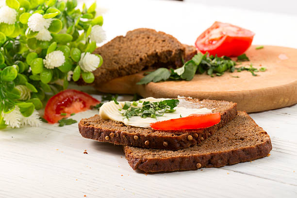Sandwiches from rye bread on a white background. Oil, tomatoes, greens on a wooden kitchen board. Close up, small depth of sharpness