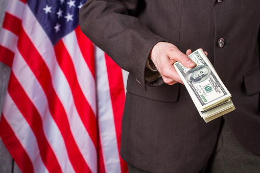 Businessman holding dollars beside flag. US flag, person and money. Our country our rules. I suggest you join us.