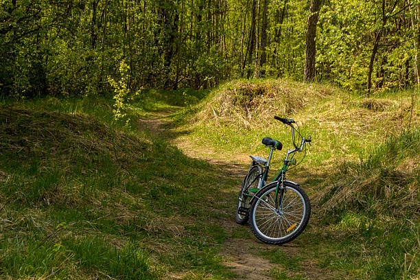 A bicycle is standing on a dirt road in the mountains against the backdrop of a beautiful evening sky, in a vertical frame.
