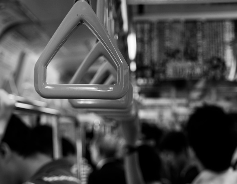 A series of triangle-shaped handles line a crowded Tokyo subway.