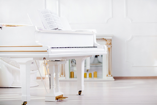 white grand piano standing in elegant white interior 
