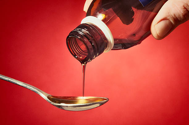 наливать некоторые сироп от кашля - cough medicine spoon medicine liquid стоковые фото и изображения