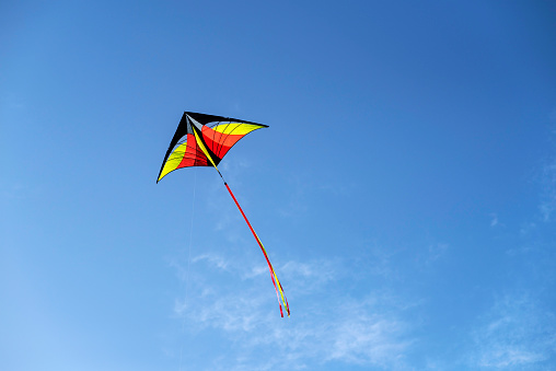 Colorful kite is flying in a blue sky.