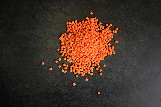 Red lentils on black cutting-board (close up)