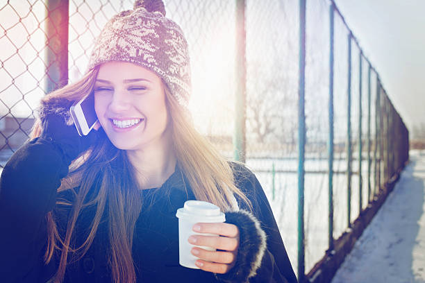 Felice Ragazza adolescente con un caffè da asporto parlando su smartphone - foto stock