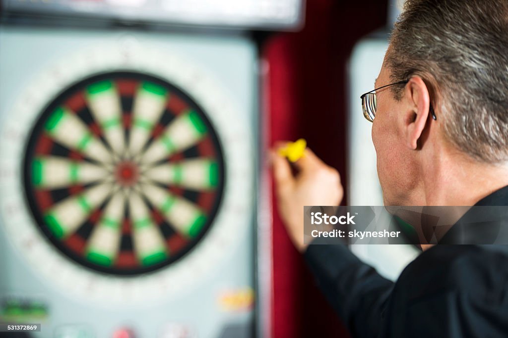 Man playing darts. Rear view of a mature man playing darts. Darts Stock Photo