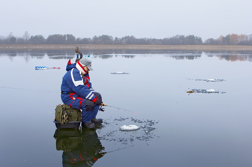 Ice fishing on a frozen lake with a layer of water