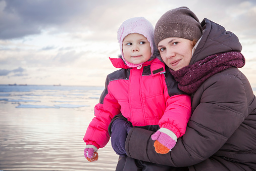Caucasian family outdoor portrait on winter sea coast, young mot