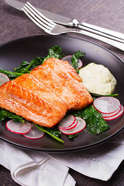 istock Broiled salmon with radish and spinach, served on black plate. 531396224