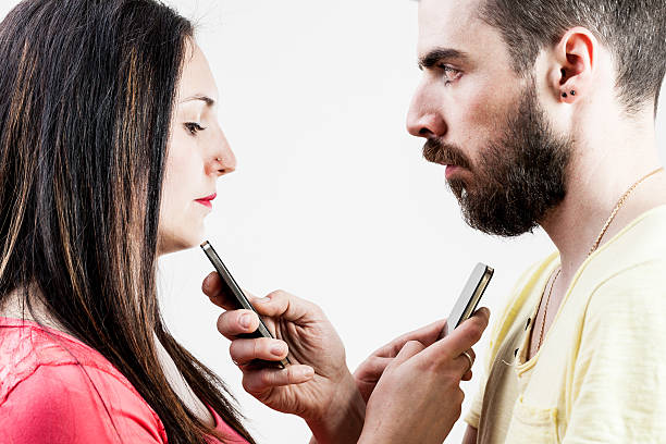 woman man and smart phones woman in front of a man each holding a smartphone instead of talking to the other one divergent movie review stock pictures, royalty-free photos & images