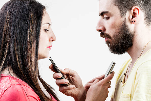 woman man and smart phones woman in front of a man each holding a smartphone instead of talking to the other one divergent movie review stock pictures, royalty-free photos & images