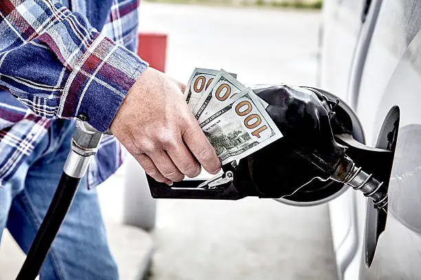 Photo of Mans Hand holding Cash while Refueling Vehicle
