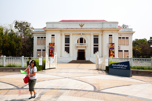 Chiang Mai, Thailand - February 26, 2013: Lanna Folklife Museum in Chiang Mai. View to entrance from sidewalk. A Thai woman is coming from museum. In background a man is walking.