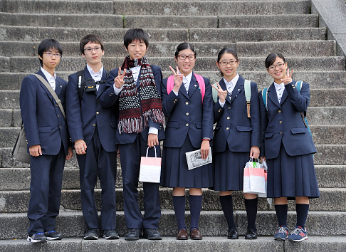Kyoto,Japan - November 4, 2014: Group of Japanese high school students dressed in a blue school uniform, looking at the photographer and some making a peace sign at Kiyomizu-dera Temple. November 4, 2014 Kyoto, Japan