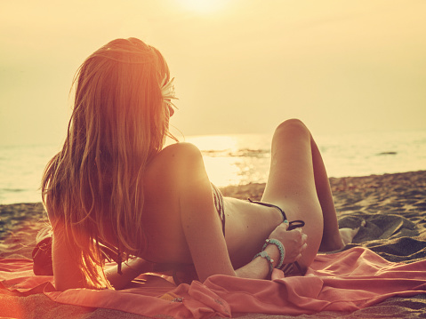 young woman relaxing on the beach during a sunset.