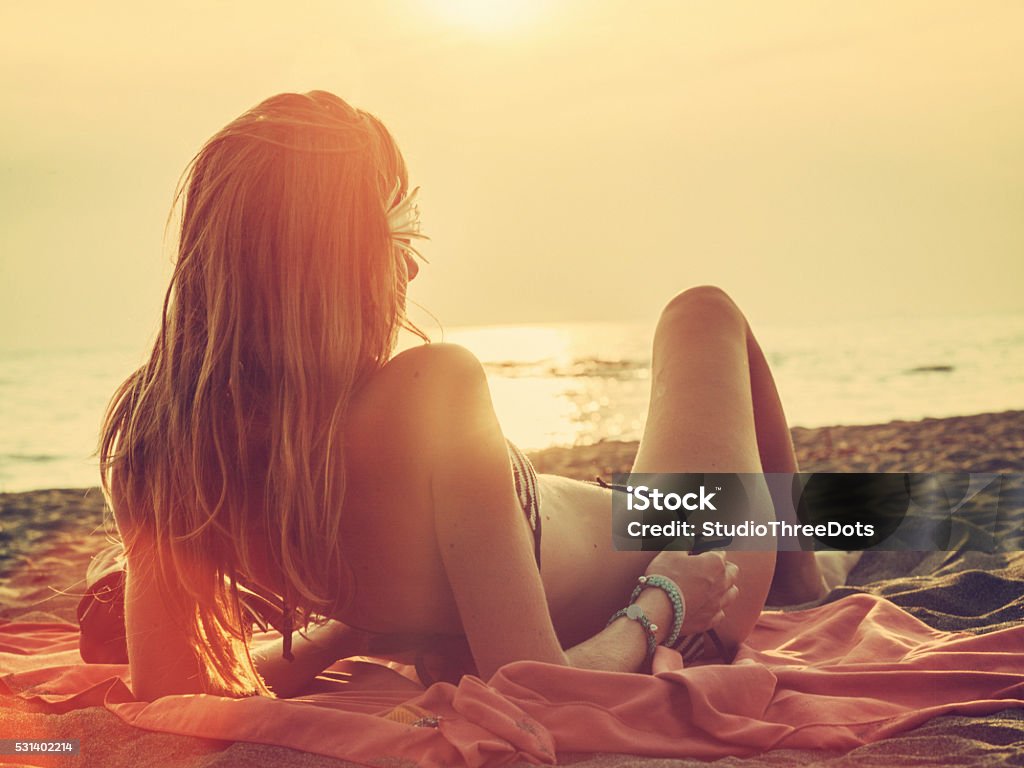 Woman relaxing on beach young woman relaxing on the beach during a sunset. Beach Stock Photo