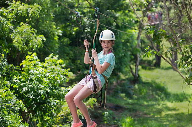 Little girl riding a zip line in tropical forest Happy smiling little girl riding a zip line in a lush tropical forest while on family vacation canopy tour photos stock pictures, royalty-free photos & images