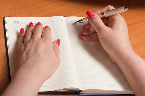 istock Female hands with manicure over pages of a notebook 531405742