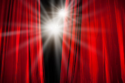 Red Curtain Opening with Stage Lights Shining Through