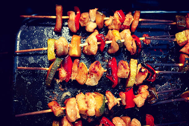Chicken teriyaki kebabs with vegetables on black baking, toned