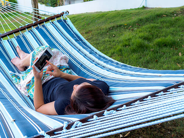 istock Woman laying down on hammock, using smart phone in garden 531413346