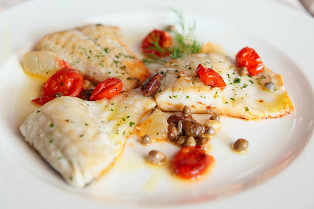 Fried fish fillet with capers and tomatoes Fried fish fillet with capers and tomatoes in plate sea bass stock pictures, royalty-free photos & images