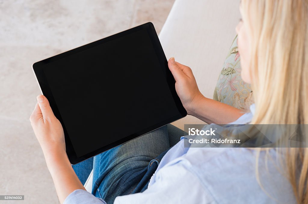 Woman working on tablet High view of woman working on digital tablet with black screen. Mature woman sitting on couch and using laptop. Close up of woman surfing net with digital tablet. Digital Tablet Stock Photo